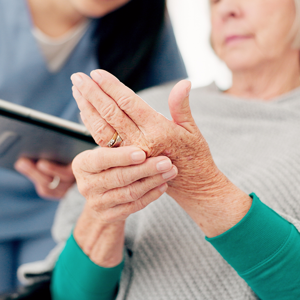 Hands, talking and a woman with a doctor for a consultation, arthritis problem or joint pain. Healthcare, home care and a senior patient speaking to a nurse about a finger accident with notes